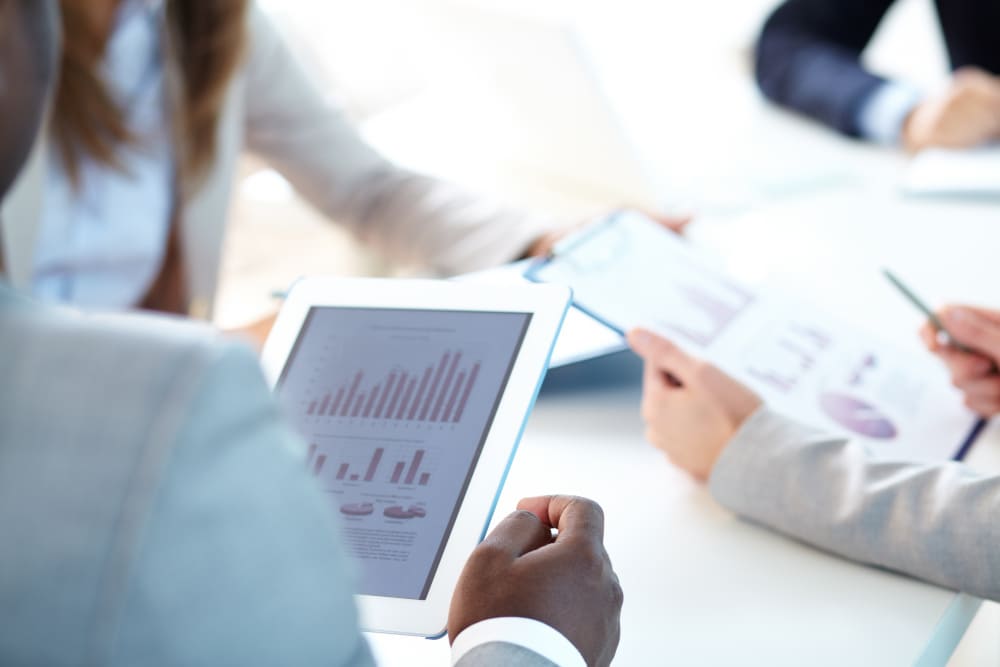 mensen kijken op een ipad waar gegevens op staan.