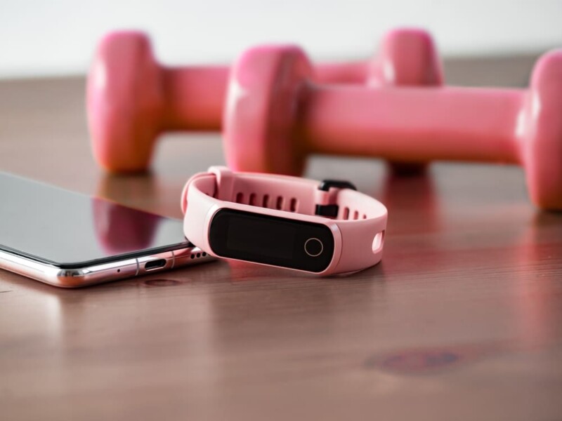 fitnessgadgets en dumbells op een houten vloer