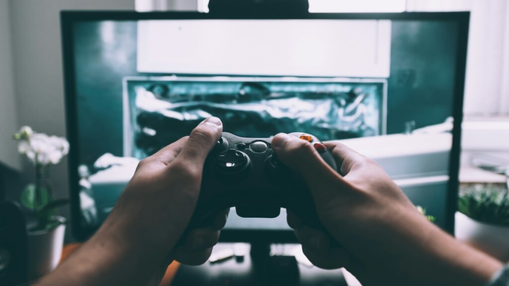 Persoon speelt videogame met controller op scherm, voorbeeld van gamification beursstand die interactie stimuleert