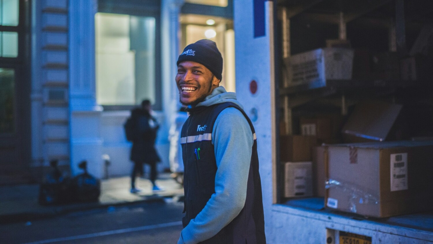 Lachende koerier naast bezorgbus tijdens avondlevering binnen enkele uren