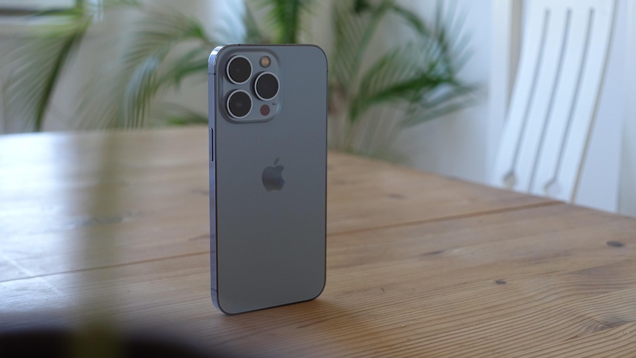 Refurbished toestel met glanzende behuizing en driedubbele camera op houten tafel, focus op iPhone-design